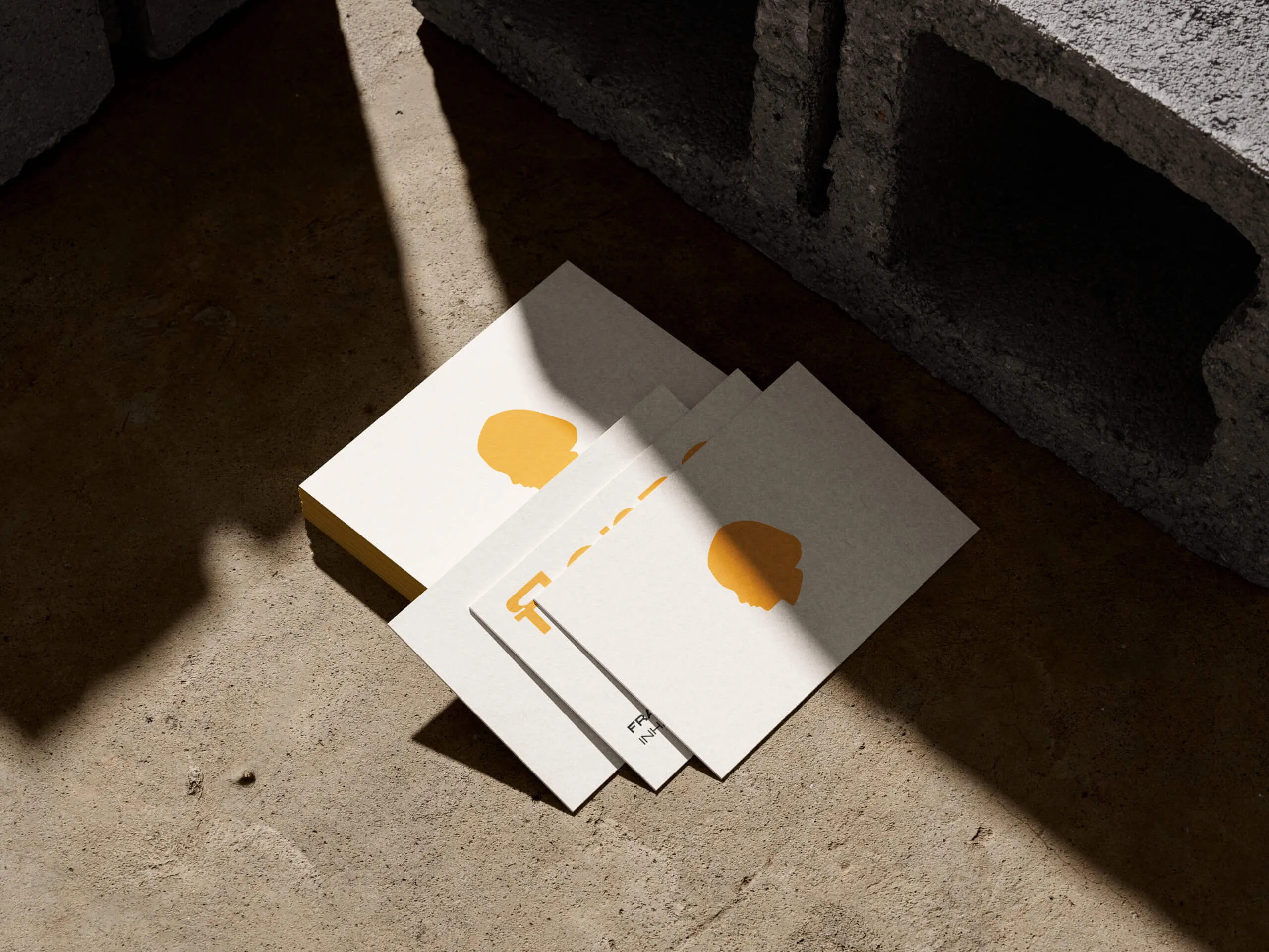 Visitenkarten mit orangem Kreisornament auf Beton im Streiflicht