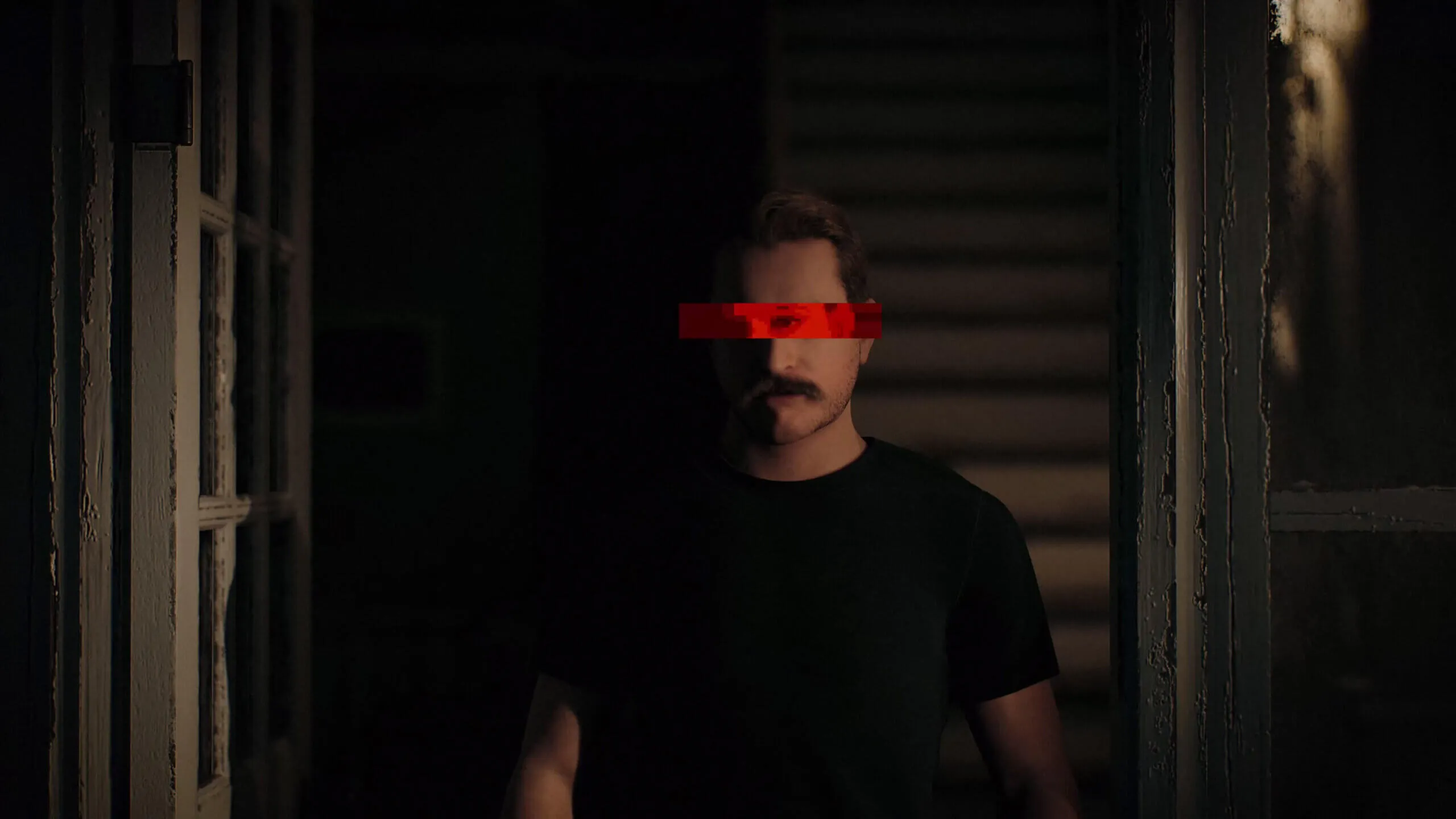Micha Kunze in einem dunklen Raum, ein roter Balken liegt über seinen Augen