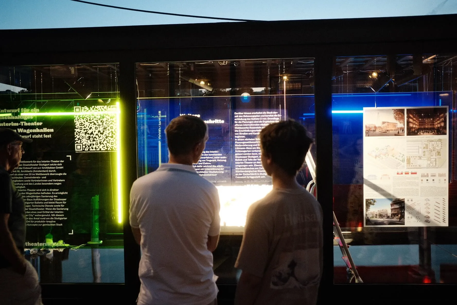 Zwei Besucher betrachten nachts eine beleuchtete Ausstellungsvitrine
